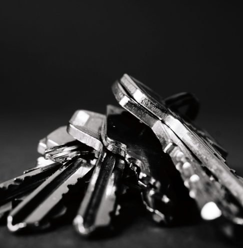 A close-up shot of a pile of metallic keys on a dark surface, emphasizing security and precision.